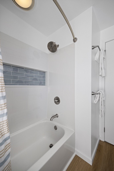 Full-size bathtub with tiled backsplash, perfect for relaxing after beach days.