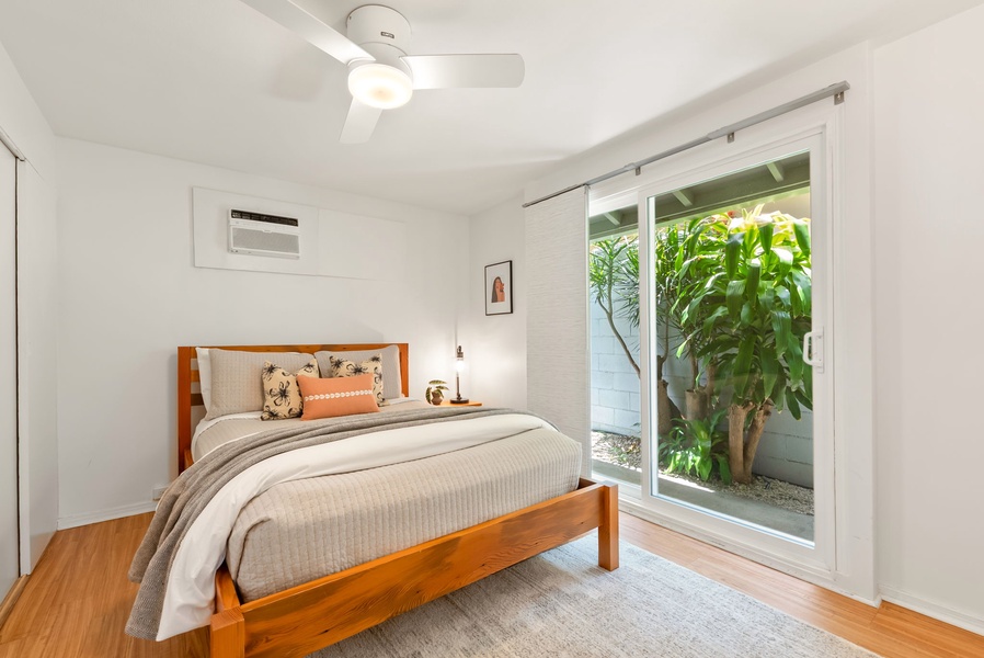 Wake up refreshed in this serene bedroom with lush garden views through sliding glass doors. Enjoy climate control with AC and ceiling fan, plus a cozy retreat designed for your comfort.
