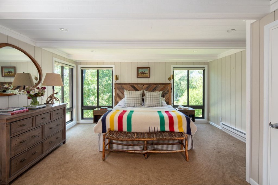 Primary suite features a plush queen bed and lots of natural lighting from the large windows.