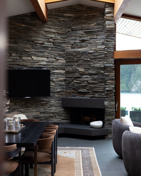 Cozy up by your dramatic stone fireplace where natural light streams through soaring windows, creating the perfect spot for morning coffee or evening relaxation.