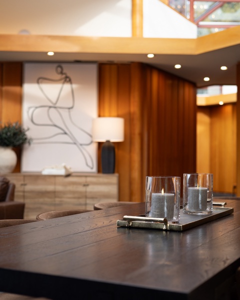 Unwind in your sophisticated living space where warm wood tones and soft candlelight create the perfect atmosphere for relaxation.