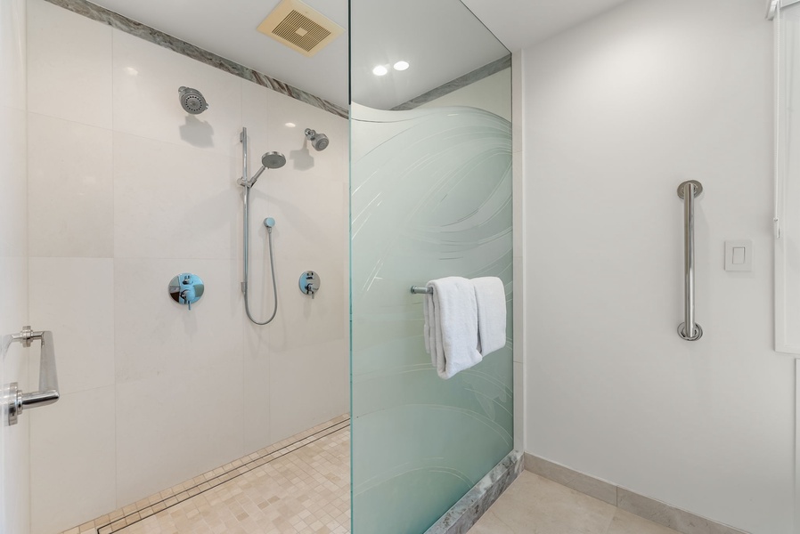 Walk-in rainfall shower with glass enclosure offers a spa-like rinse after beach adventures.