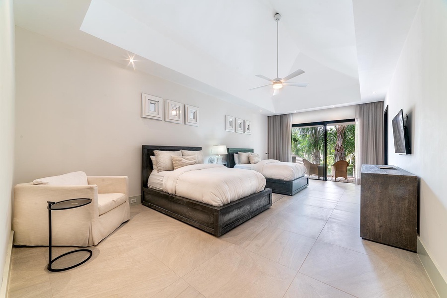 Spacious guest bedroom with two plush queen-size beds and a private balcony offering garden views.