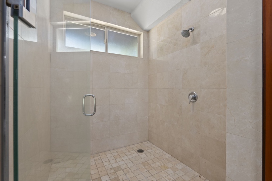 Walk-in shower with sleek tile and glass door.