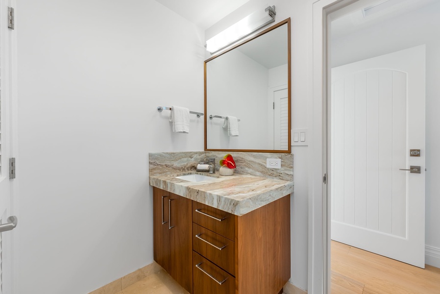 Elegant ensuite bath with granite countertops and tropical wood cabinetry for a touch of refinement.