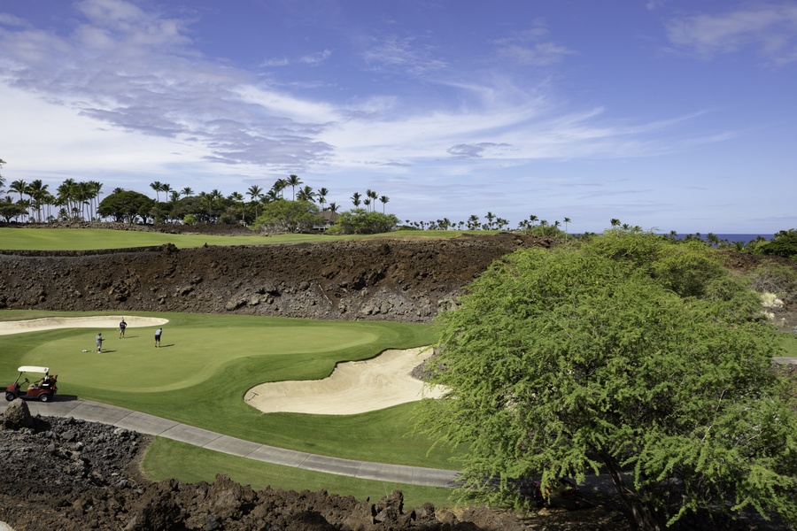 Championship golf course with dramatic lava rock formations and tropical palm trees creating a stunning Hawaiian landscape.