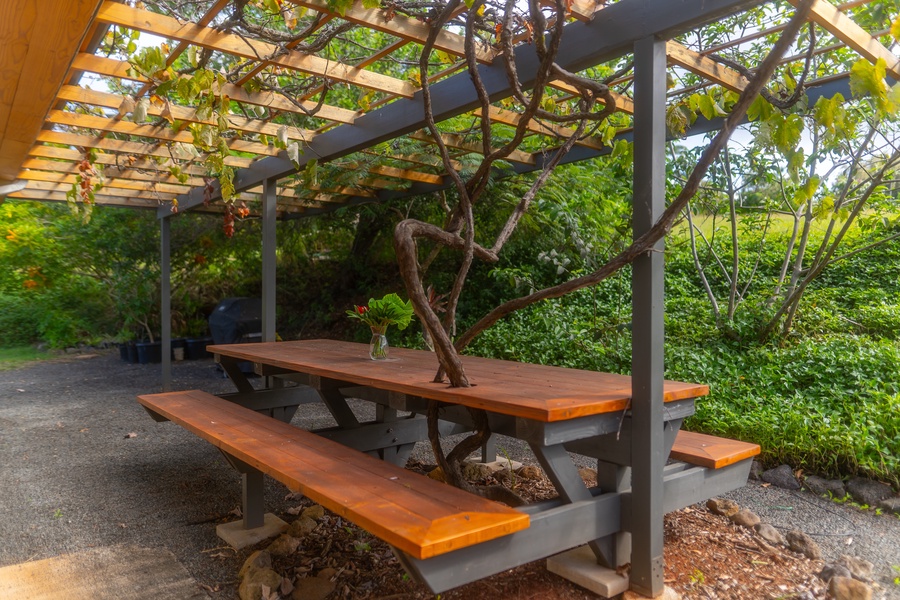 Gather for open-air meals at a shaded picnic table surrounded by lush tropical greenery.