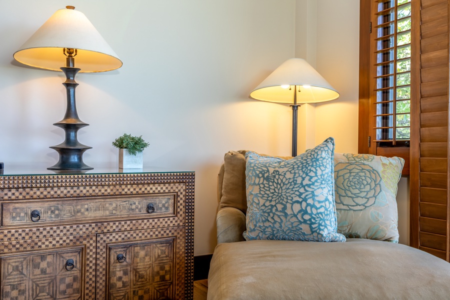 Curl up in your cozy reading chair with soft blue pillows, warm lighting creating the perfect ambiance for relaxation.