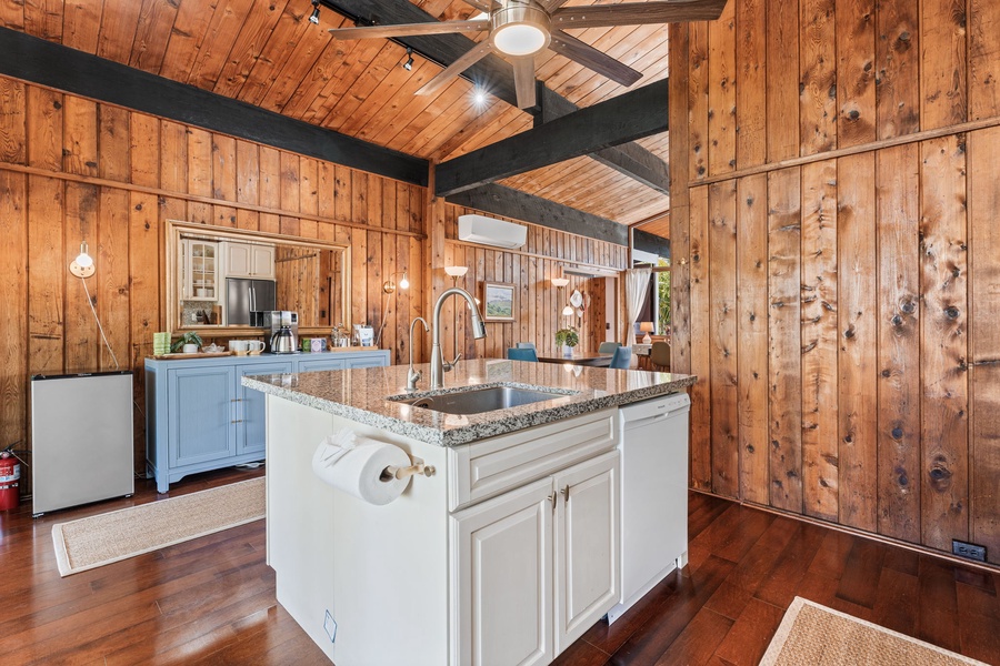 Your equipped kitchen blends cozy cabin charm with modern convenience, featuring granite countertops and warm wood ceilings.