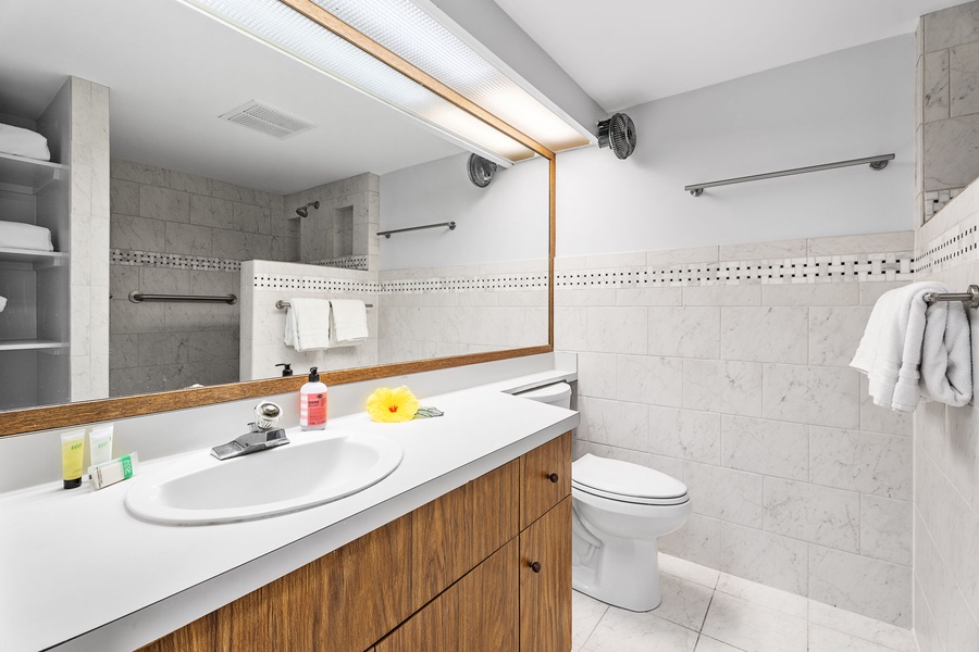 Bright bathroom with a large mirror and wood-accented vanity.