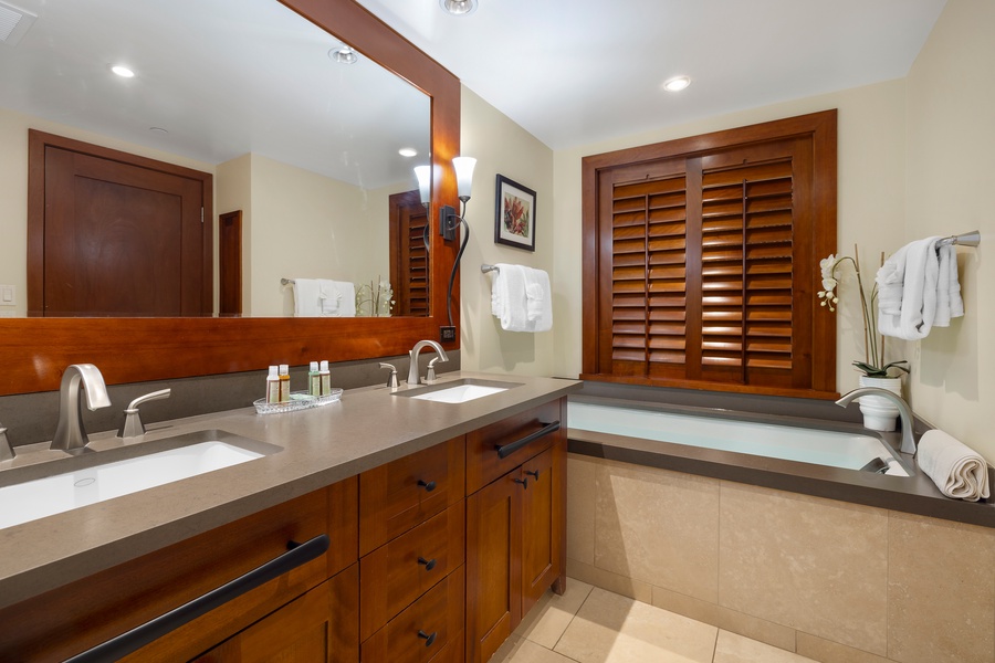 Unwind in your elegant bathroom featuring dual vanities, a deep soaking tub, and rich wood finishes that create a spa-like retreat.
