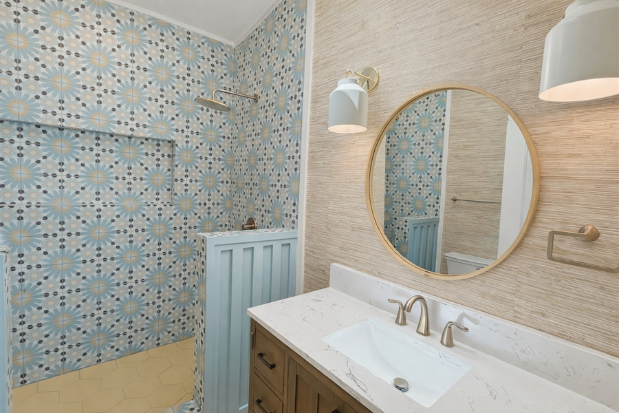Enjoy a stylishly appointed bathroom featuring gorgeous patterned tile, elegant marble countertops, and brass accents that create a luxurious retreat.