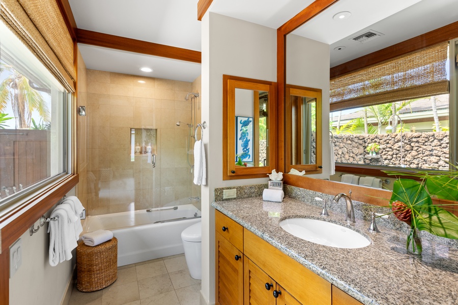 Third en-suite bathroom with tub/shower combo, custom vanity, and tropical wood finishes.