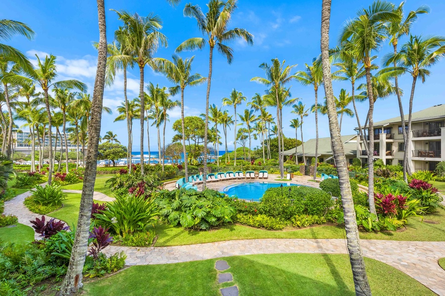 Tropical resort paradise with sparkling pool surrounded by swaying palms and lush gardens, steps from the ocean.