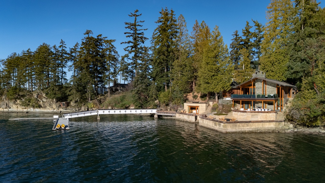 Waterfront retreat with private dock on pristine lake, surrounded by towering evergreens and peaceful natural landscape.