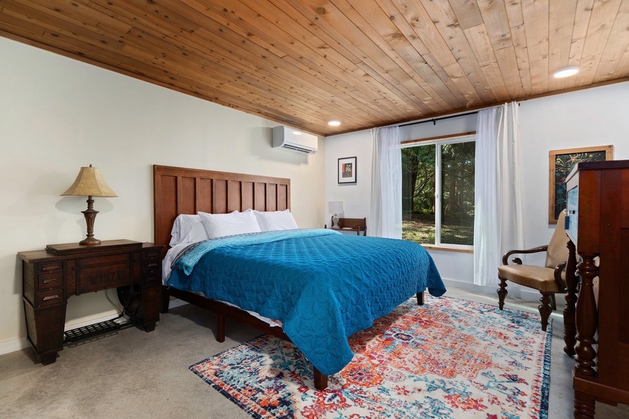 The primary bedroom features a king-size bed, wood ceiling, and playful decor for a cozy night’s sleep.