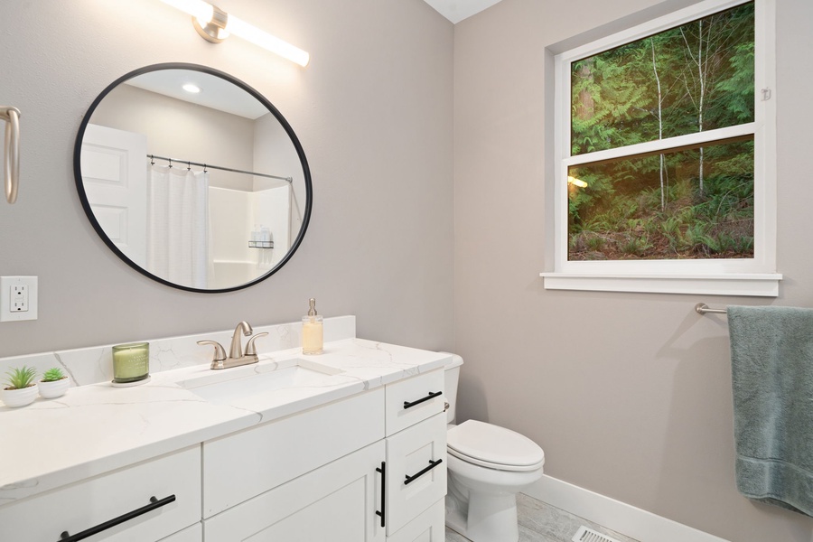 Step into your bright, beautifully appointed bathroom with forest views from the window, creating a peaceful retreat for your morning routine.
