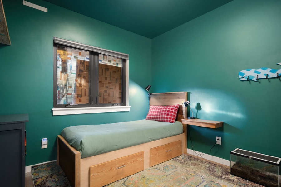 Unwind in this vibrant green bedroom with cozy single bed, built-in storage, and warm wooden touches.