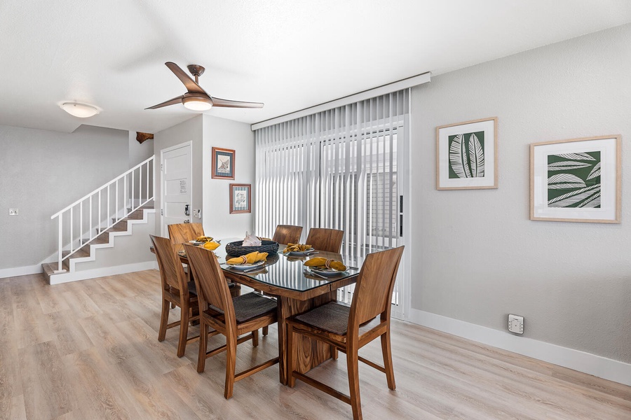 Dining area with seating for six and natural light filtering through vertical blinds.