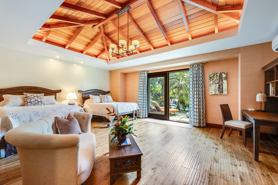 Spacious guest suite with seating area and vaulted ceilings opens to a private garden lanai.
