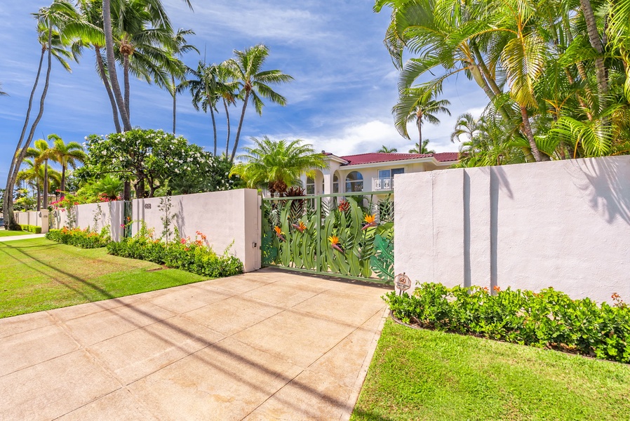 Entrance to the villa with lush landscaping and a grand gate, offering privacy and a warm welcome.