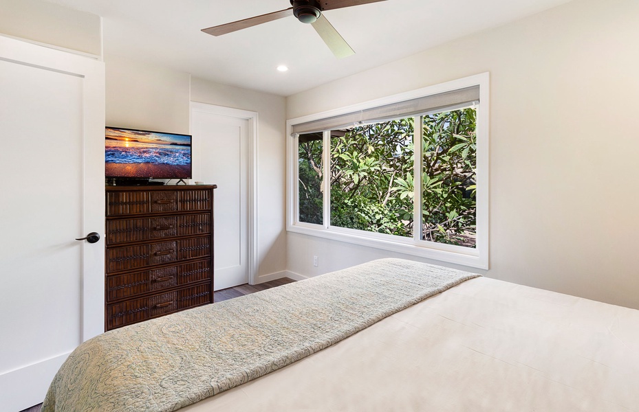 Unwind in this cozy bedroom featuring a queen-size bed and serene garden views through the window.