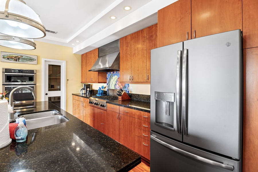 Fully equipped kitchen featuring stainless steel appliances, a sleek black countertop, and modern lighting.