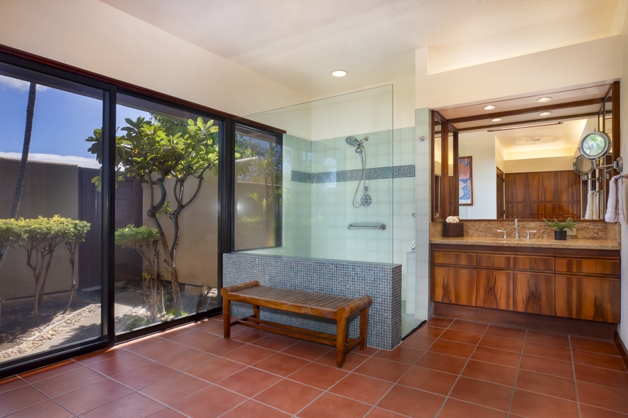 Tropical garden views and easy lanai access turn this bathroom space into a calming open-air spa experience.