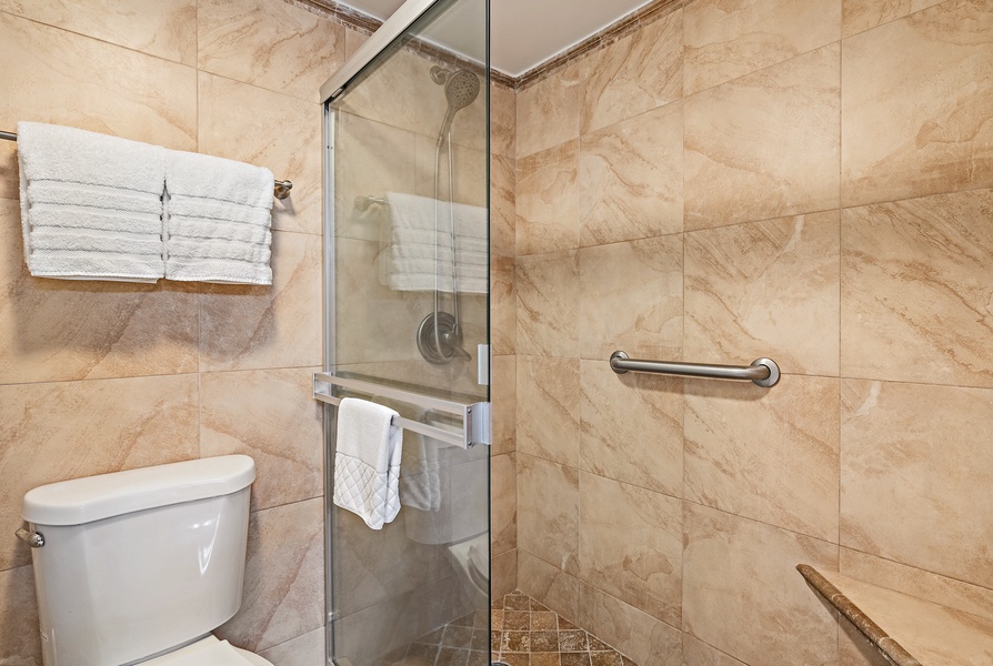 The bathroom includes a modern walk-in shower with sleek glass doors and elegant tilework for a spa-like experience.