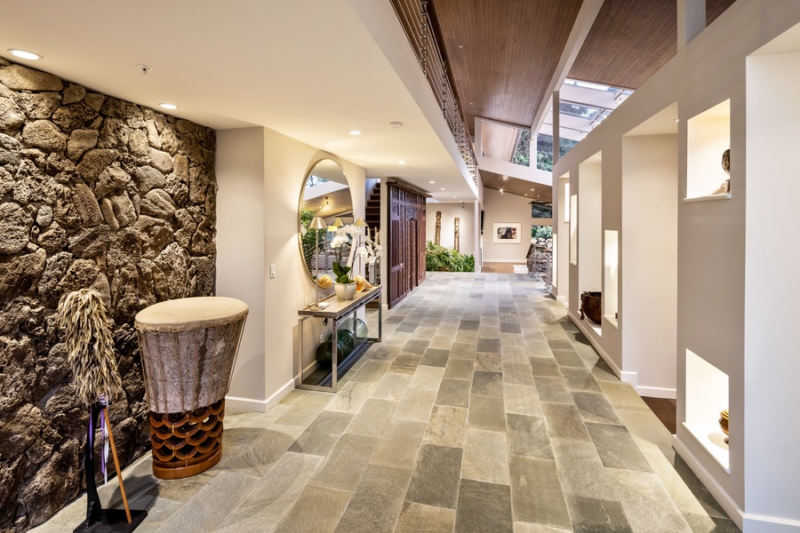 Entry hall with stone floors, gallery lighting, and indoor landscaping creates a resort-style welcome.