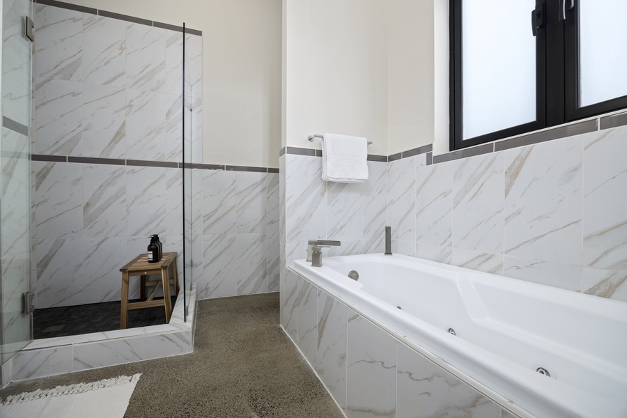Primary bath retreat with soaking tub and marble tile accents — unwind in pure relaxation.