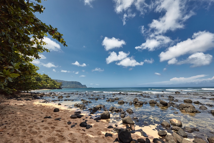 Rocky shoreline with calm waves and bright blue skies.