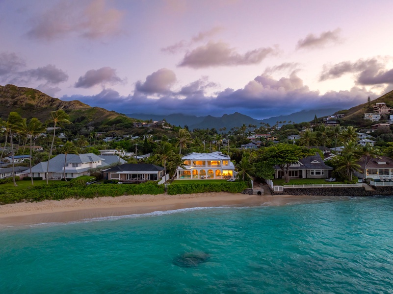 A serene twilight aerial of Mokulua Sunrise Estate as it glows against the lush Lanikai hillside.