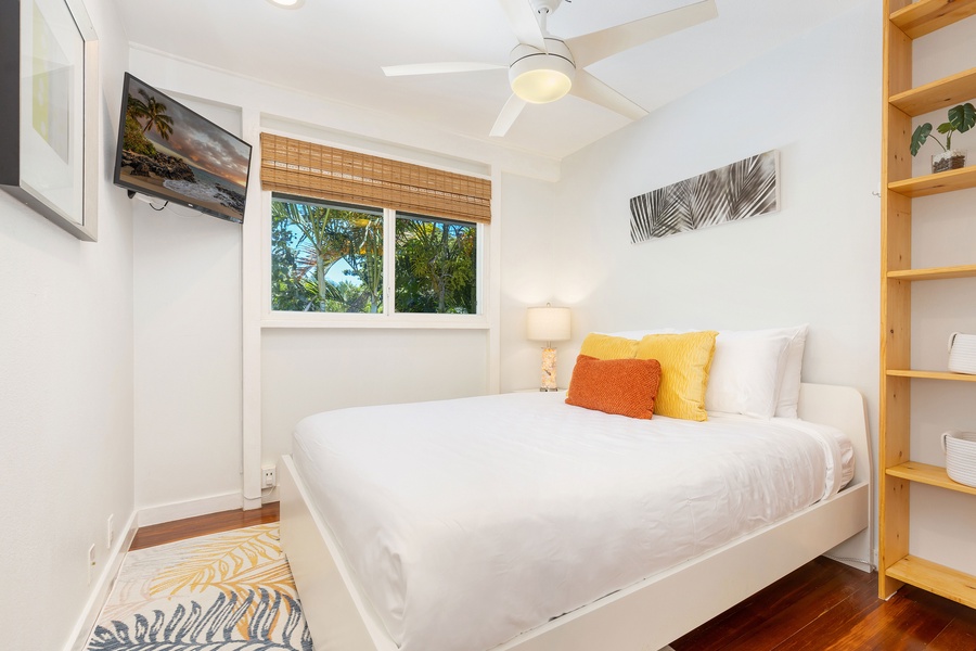Cozy guest bedroom with queen bed, smart TV, and open shelving for your beach reads and gear.