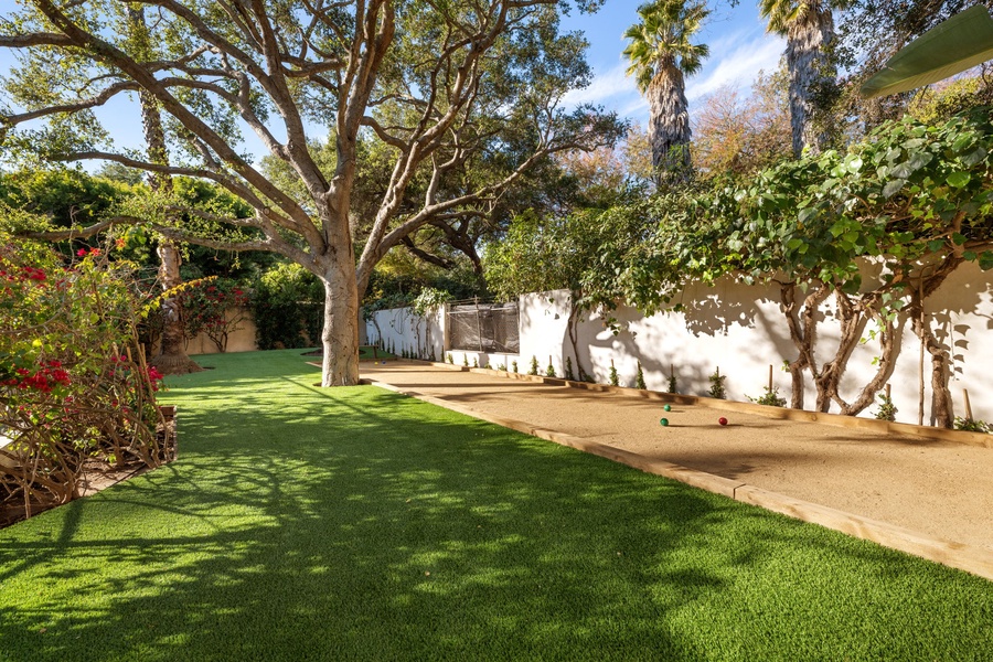 Relax in your private backyard oasis with lush green lawn, mature shade trees, and bocce ball court for friendly competition.