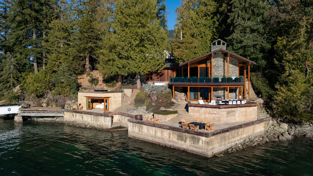 Stunning lakefront retreat nestled among towering evergreens with private dock and waterfront terrace for the ultimate escape.