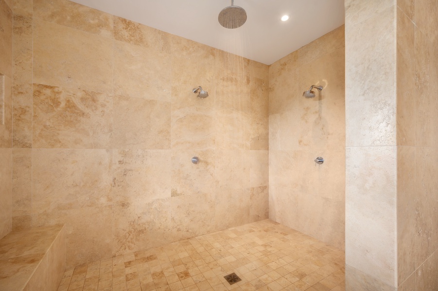 Expansive stone shower with dual showerheads, creating a luxurious spa experience in the privacy of your suite.