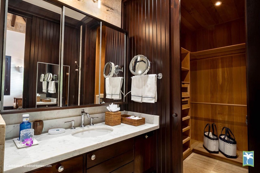 Elegant ensuite bathroom with wooden cabinetry and a walk-in closet.