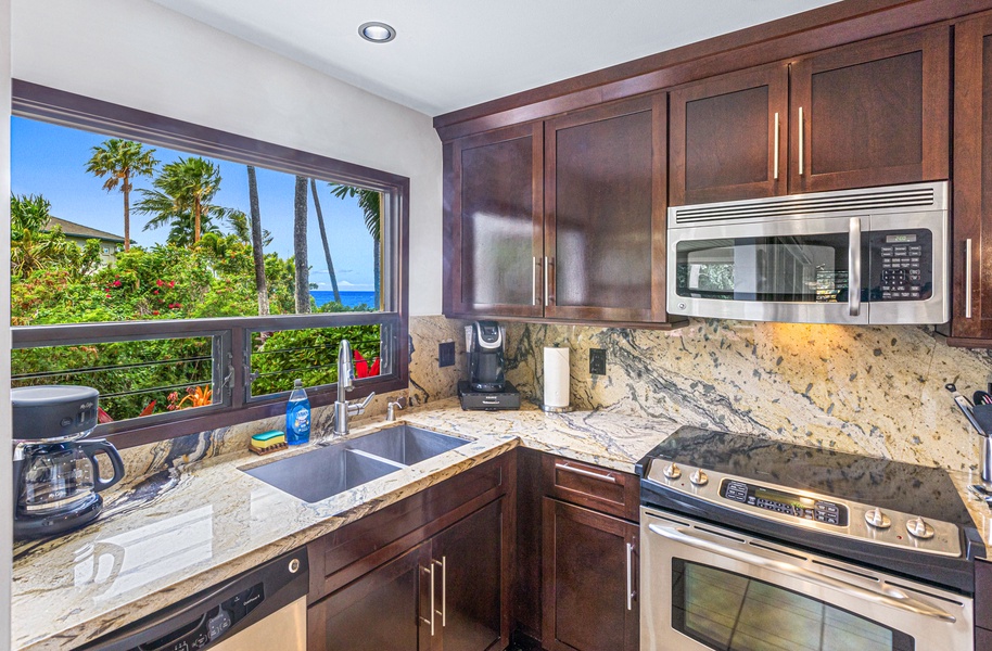 The kitchen offers modern appliances and a window with a beautiful view of the ocean and palm trees, perfect for meal prep with a scenic backdrop.