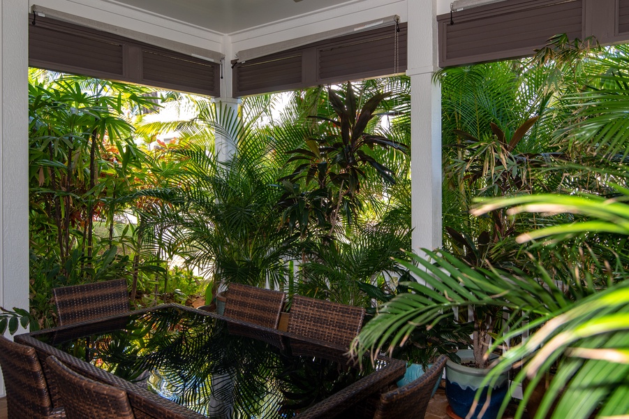 The lanai provides a dining space surrounded by tropical plants.