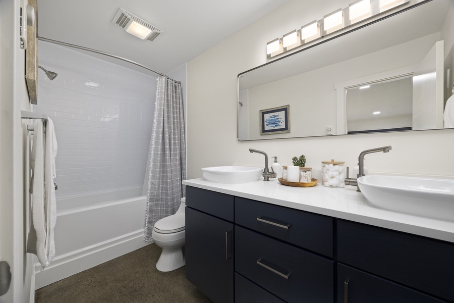 Crisp, modern bathroom with tub-shower combo and stylish vanity — clean and comfortable for all guests.