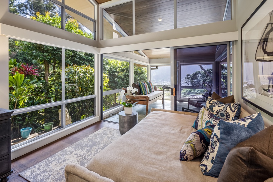 Cozy reading nook and retreat space surrounded by glass and tropical greenery.