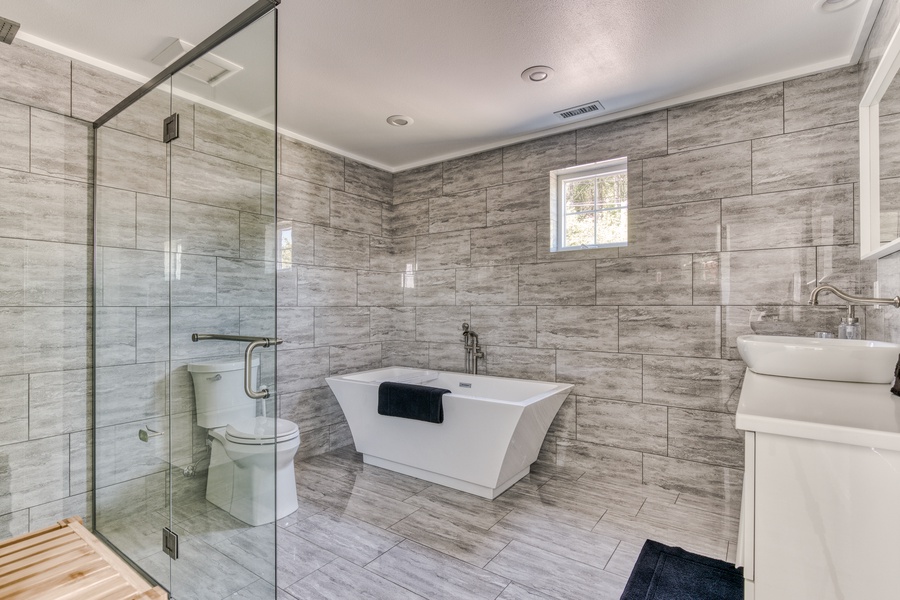 Amazing soaker tub in fully tiled primary bathroom