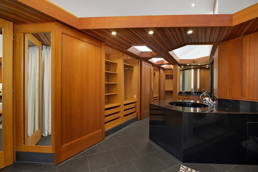 Step into your luxurious ensuite with rich wood cabinetry and sleek black marble countertops, where warm lighting creates the perfect ambiance.