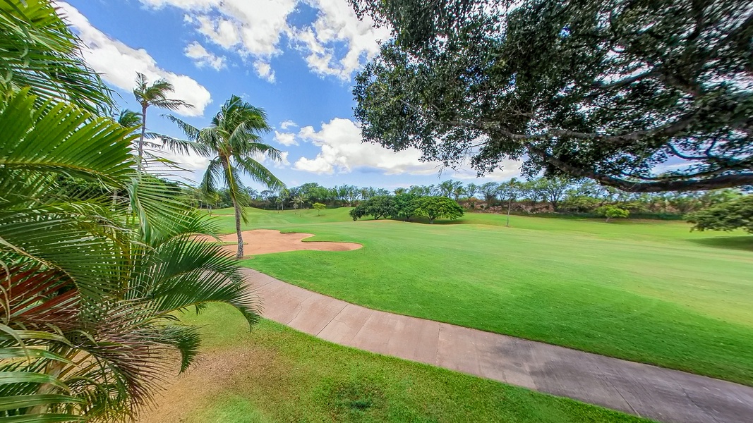 Pristine golf course with lush fairways, sand bunkers, and tropical palm trees under bright blue skies.