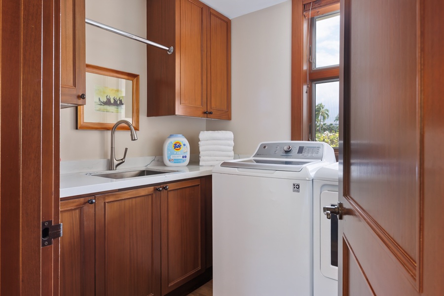 Your personal laundry room features full-size washer and dryer with rich wooden cabinetry and convenient sink for all your washing needs.