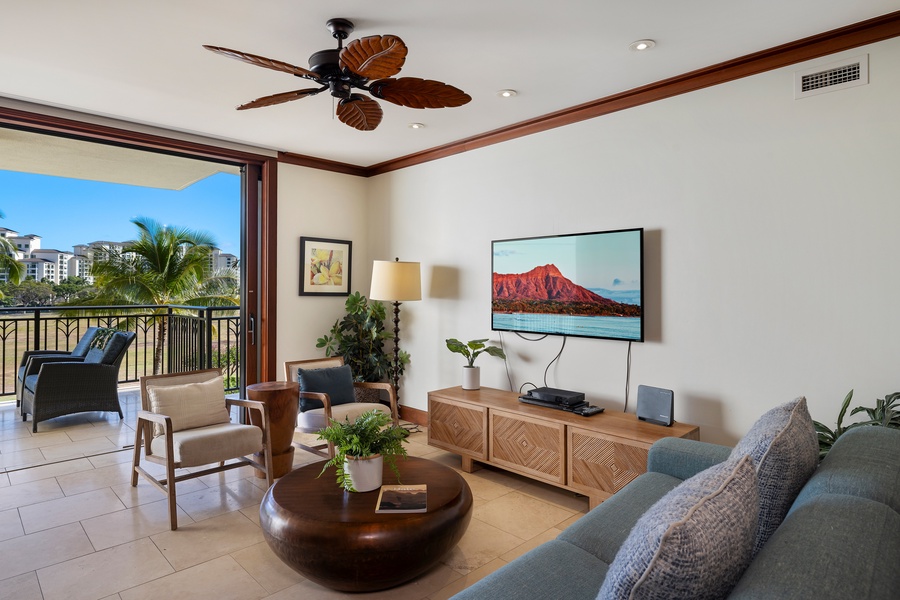 Unwind in your tropical living space with a ceiling fan, entertainment center, and balcony overlooking lush palm trees.