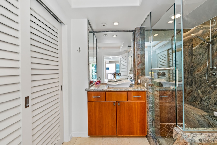 Spacious bathroom with marble walk-in shower and sleek vanity, designed for comfort and luxury.