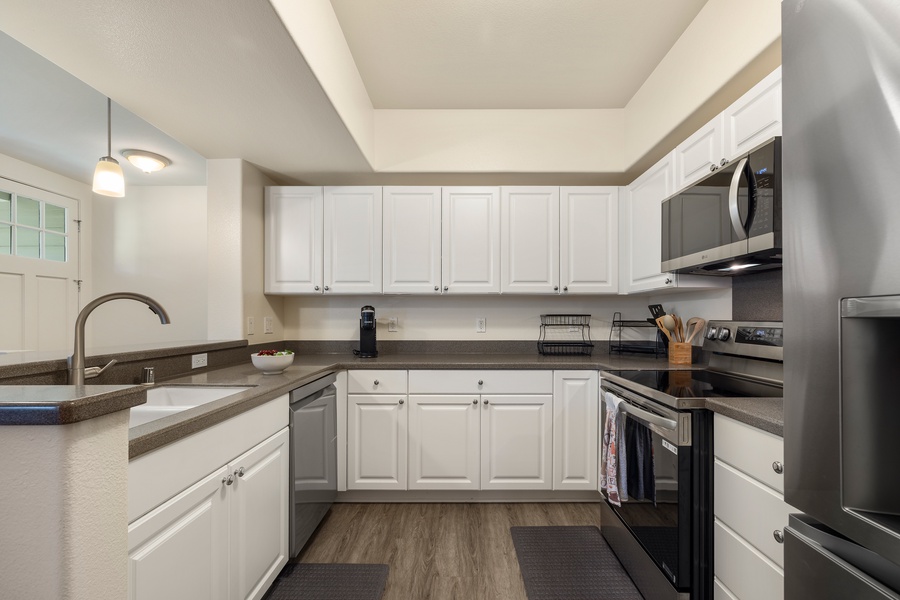 Your fully equipped kitchen features sleek white cabinets, granite countertops, and modern stainless steel appliances ready for culinary adventures.