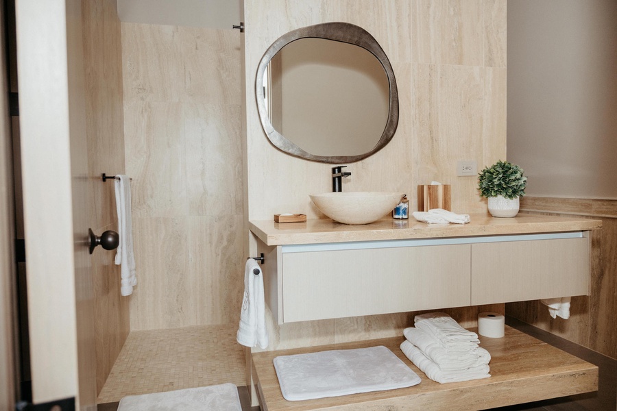 Ensuite bathroom featuring a modern vessel sink and a unique mirror design.